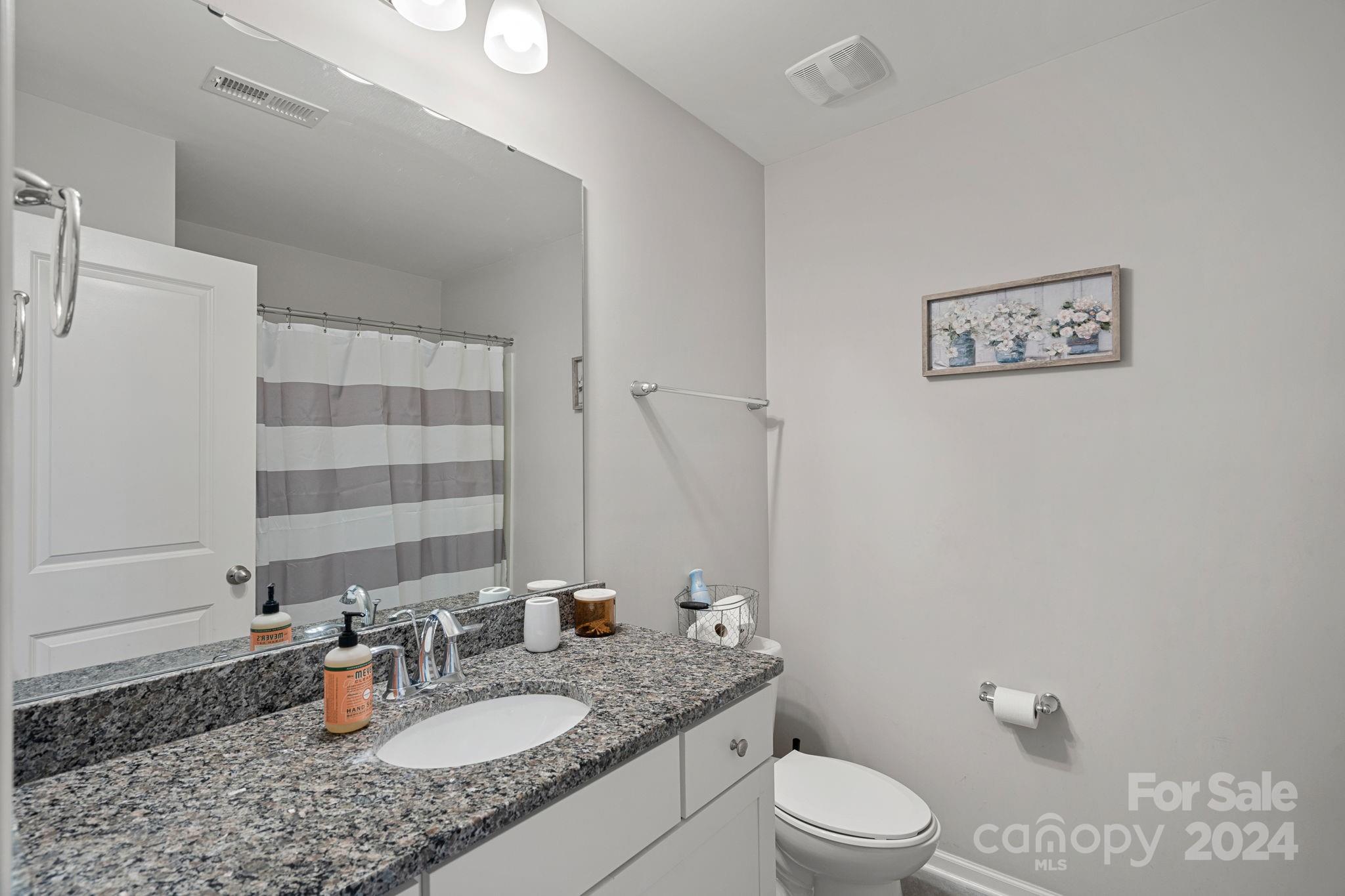 7044 Harris Bay Road Charlotte, NC 28269 - Photo 15 of 17 a bathroom with a granite countertop sink mirror vanity and toilet