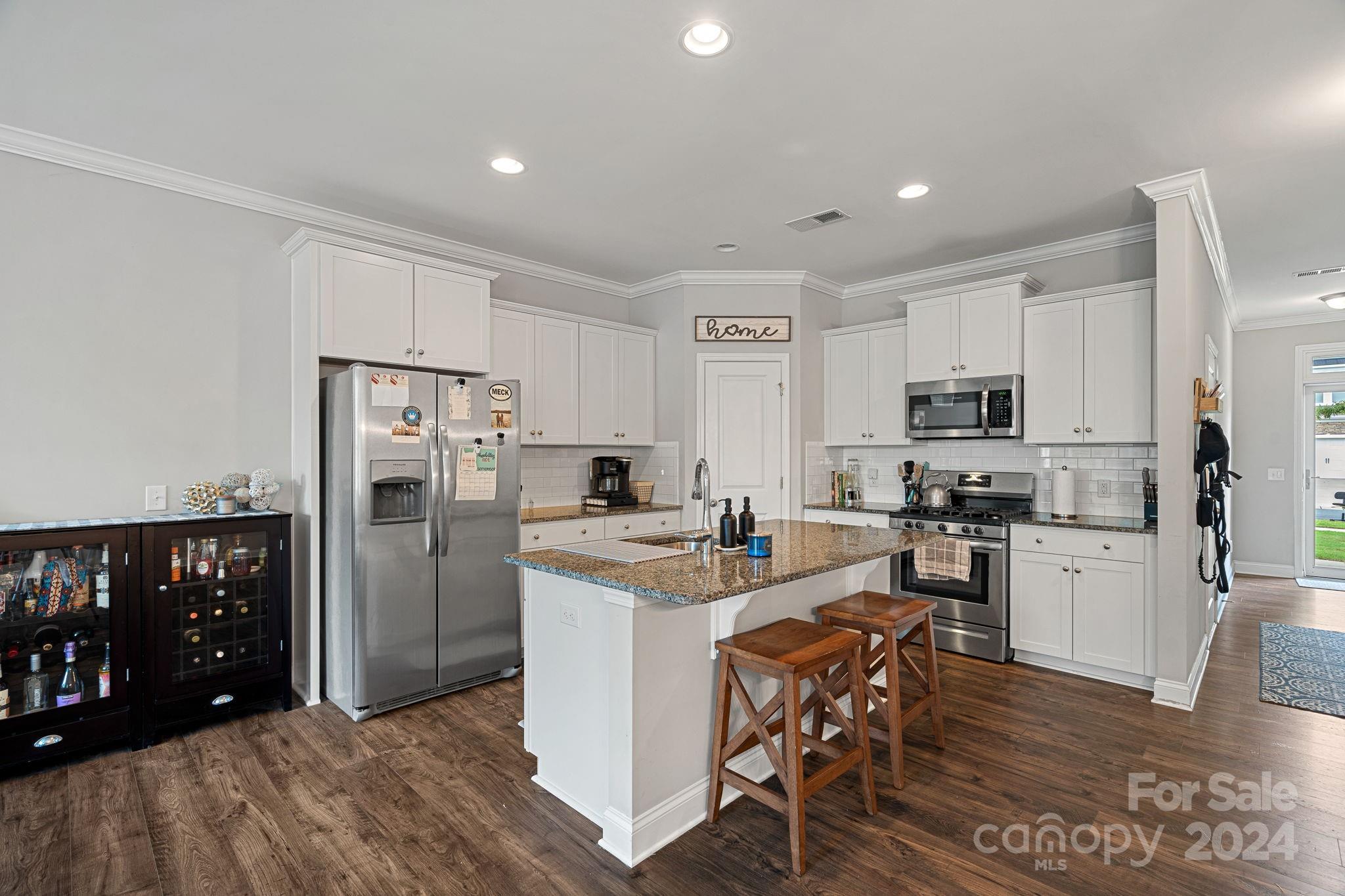7044 Harris Bay Road Charlotte, NC 28269 - Photo 6 of 17 a kitchen with stainless steel appliances a stove a refrigerator a sink a dining table and chairs
