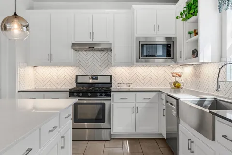 a kitchen with white cabinets and appliances
