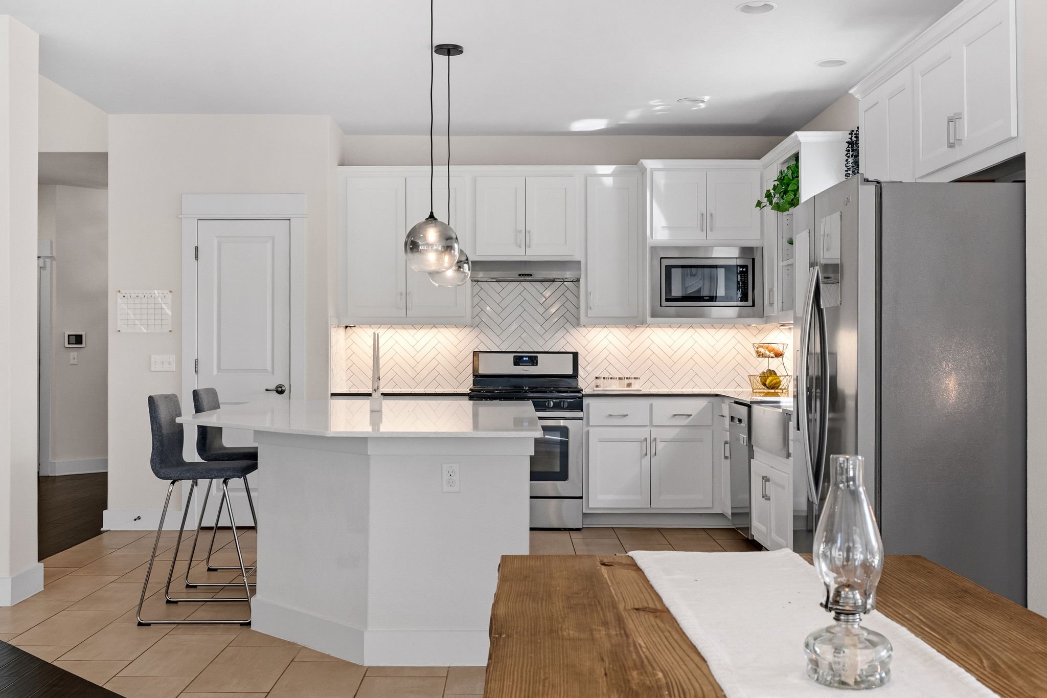 7205 Albert Road Austin, TX 78745 - Photo 5 of 37 a kitchen with kitchen island a refrigerator a stove a sink and a dining table with white cabinets