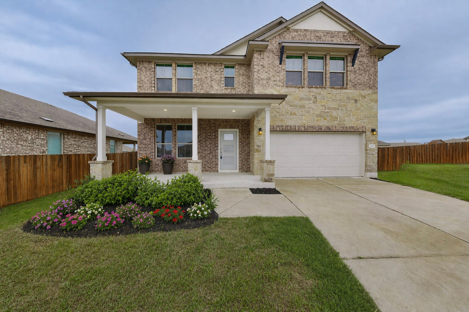 16809 Guido Cove Pflugerville, TX 78660 - Photo 1 of 40 Two-story home featuring a brick and stone facade, covered front porch with columns, a two-car garage, and a manicured front yard with a flower bed