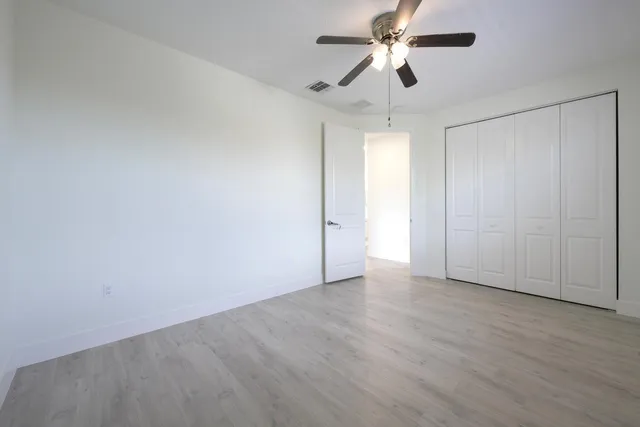 a view of an empty room and chandelier fan