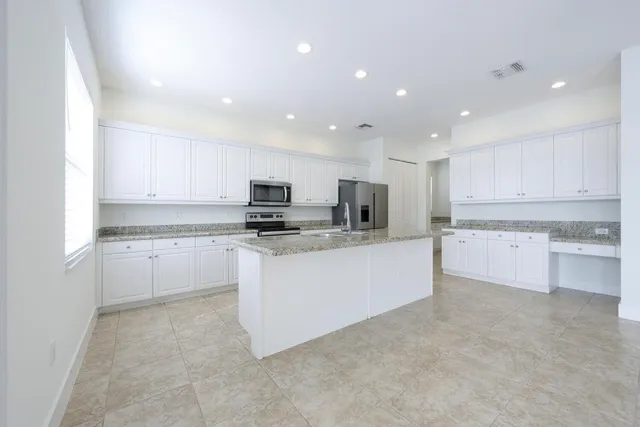 a large white kitchen with a refrigerator a stove a sink and a window