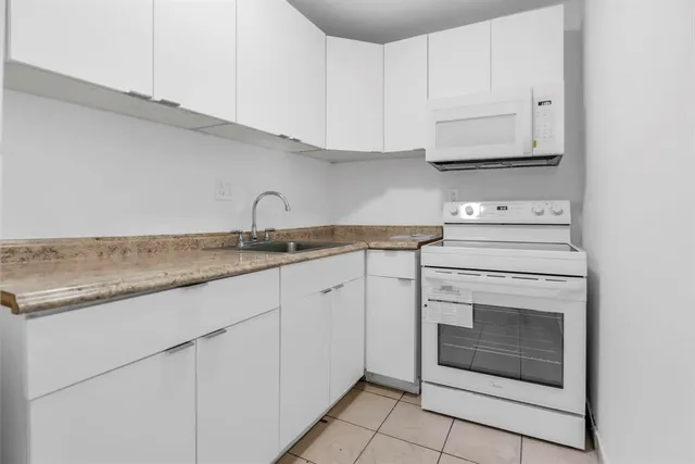 a kitchen with granite countertop white cabinets and white appliances