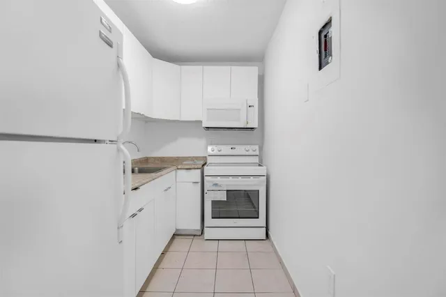 a kitchen with granite countertop white cabinets and white appliances