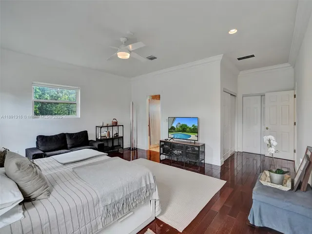 a bedroom with a bed window tv and dresser