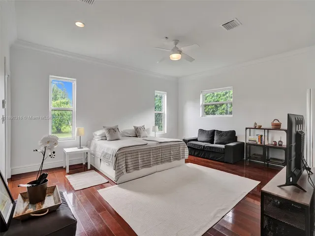 a spacious bedroom with a bed a couch and a dresser next to a window