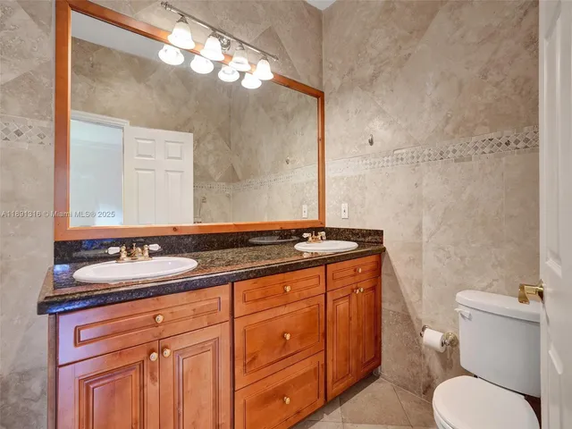 a bathroom with a granite countertop toilet sink and mirror