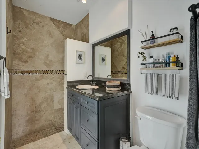 a bathroom with a granite countertop sink a mirror and a shower