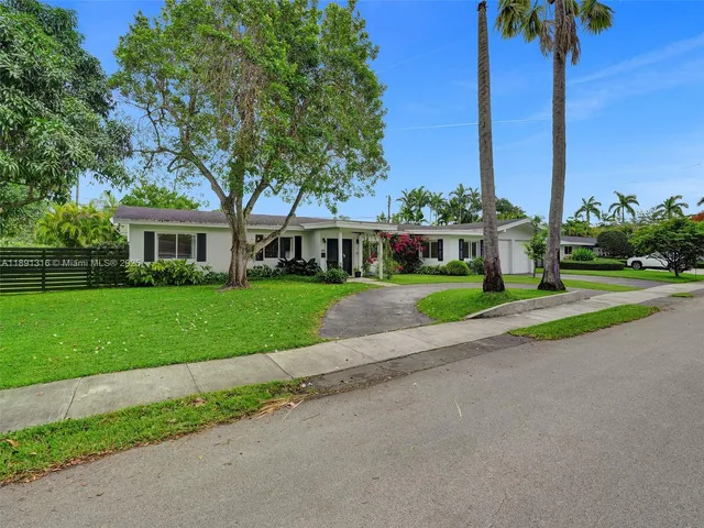 a view of a house with a big yard plants and palm trees
