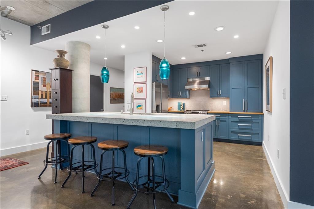 845 Spring Street Northwest, Unit 129 Atlanta, GA 30308 - Photo 1 of 48 a kitchen with stainless steel appliances granite countertop table chairs sink and cabinets