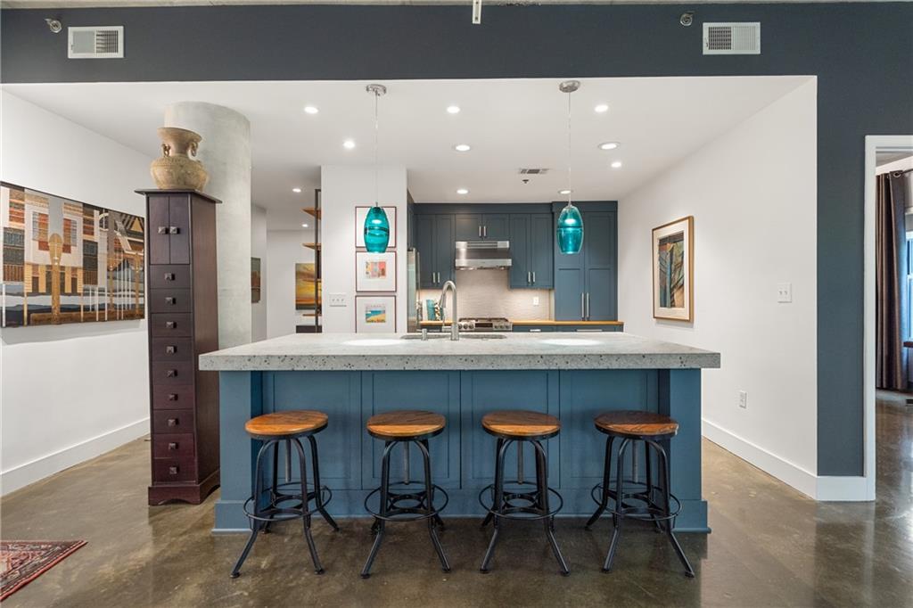 845 Spring Street Northwest, Unit 129 Atlanta, GA 30308 - Photo 16 of 48 a kitchen with stainless steel appliances kitchen island granite countertop a table chairs sink and cabinets