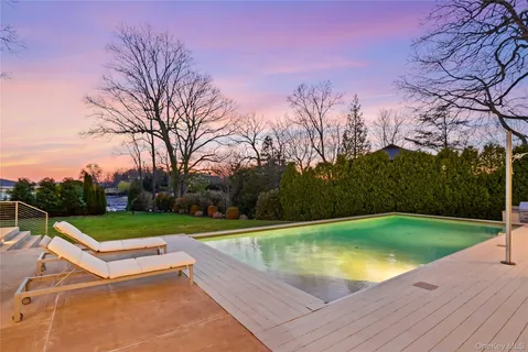a view of a swimming pool with a yard and a large tree