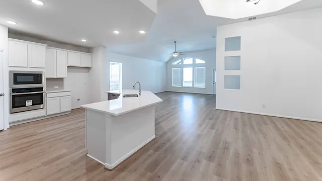 a large kitchen with stainless steel appliances a large counter top a wooden floors and a fireplace