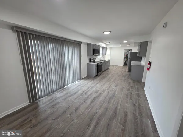 a kitchen with stainless steel appliances a stove top oven a sink a refrigerator white cabinets and wooden floor