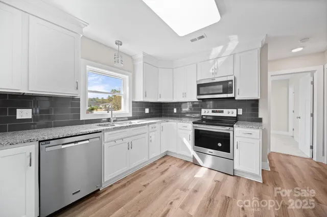 a kitchen with granite countertop white cabinets and appliances