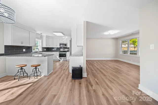 a kitchen with stainless steel appliances granite countertop a stove top oven a sink dishwasher and a refrigerator with wooden floor