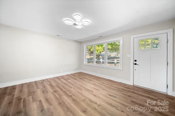 an empty room with wooden floor fan and windows