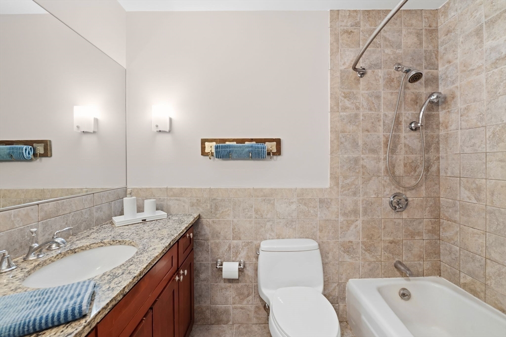 60 Brackett Place, Unit D Marblehead, MA 01945 - Photo 24 of 30 a bathroom with a granite countertop sink a toilet a mirror and bathtub