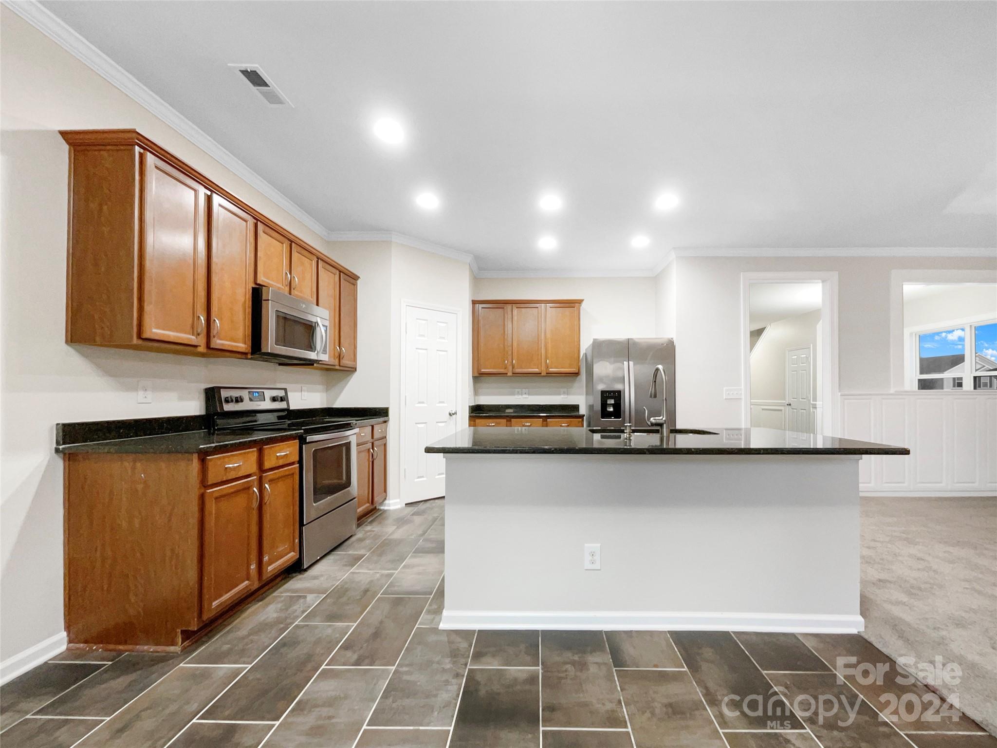 1005 Garden Web Road Indian Trail, NC 28079 - Photo 14 of 25 a large kitchen with stainless steel appliances a stove a sink a refrigerator and microwave