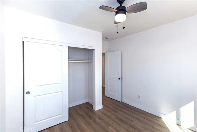 an empty room with wooden floor chandelier and fan