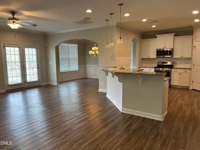 an open kitchen with kitchen island wooden floors and stainless steel appliances
