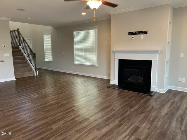 a view of an empty room with wooden floor fireplace and a window