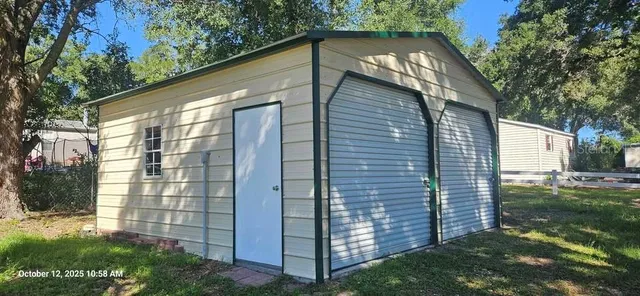 a backyard of a house with plants and large tree