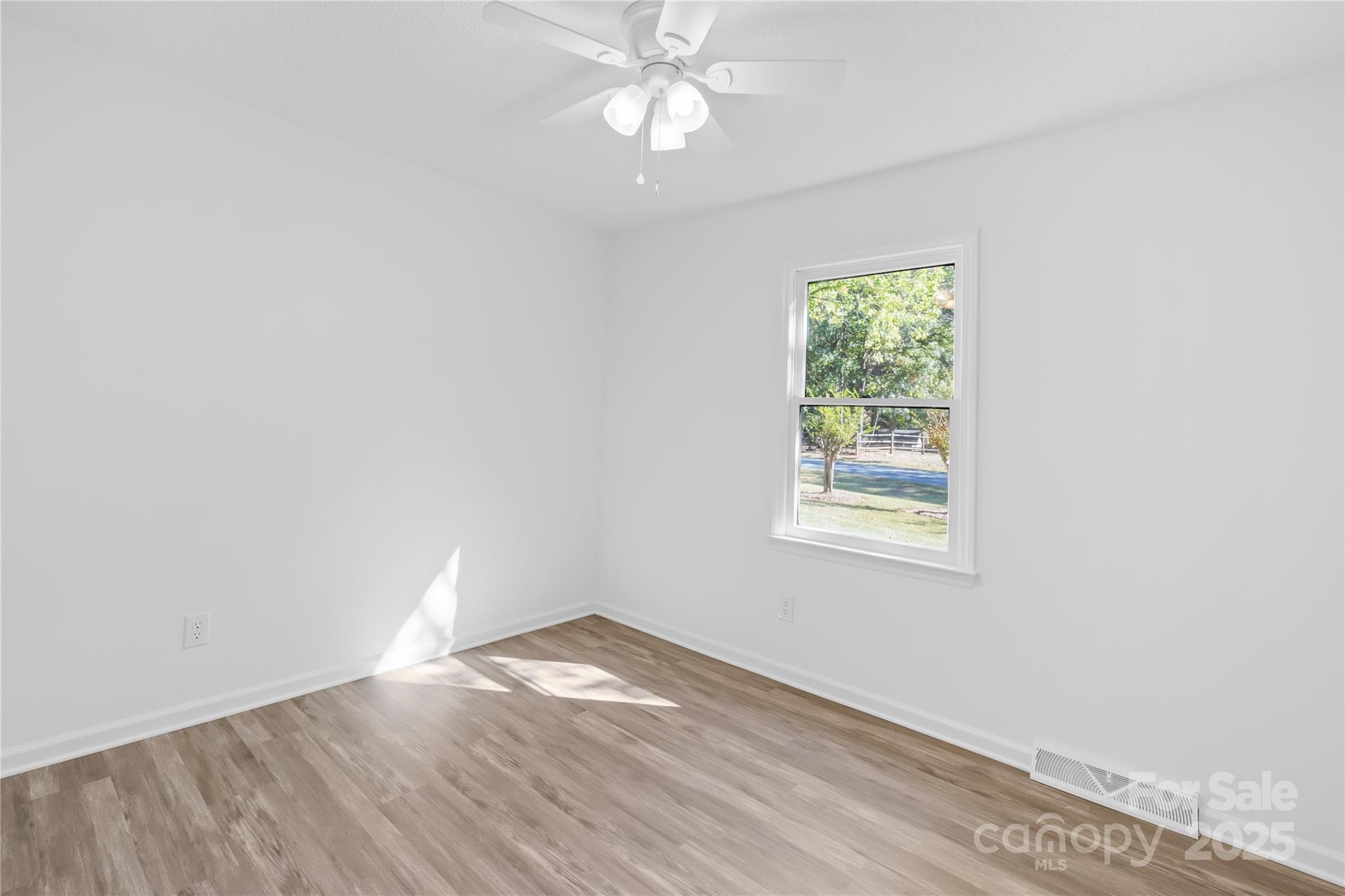 700 Chestnut Lane Matthews, NC 28104 - Photo 23 of 39 an empty room with wooden floor chandelier fan and windows