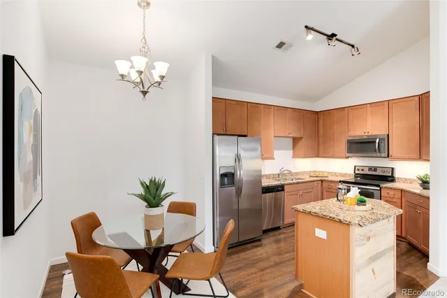 a kitchen with stainless steel appliances granite countertop a stove refrigerator a dining table and chairs with wooden floor