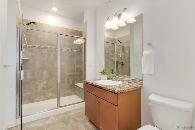 a bathroom with a granite countertop sink toilet a mirror and shower