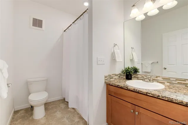 a bathroom with a granite countertop sink a toilet and a mirror