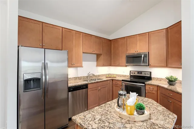a kitchen with stainless steel appliances granite countertop a sink a stove a microwave a refrigerator and cabinets