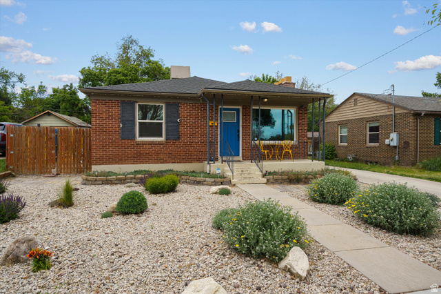 961 33rd Street Ogden, UT 84403 - Photo 34 of 39 Brick exterior featuring a covered front porch with iron railings, a vibrant blue entry door, and dark window shutters