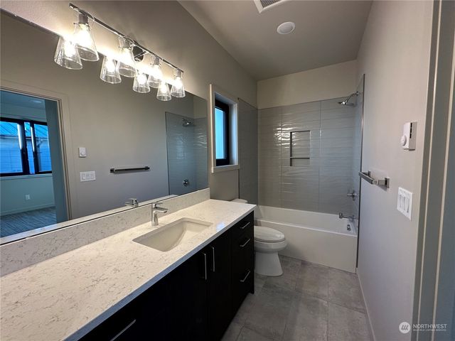 a bathroom with a granite countertop sink a toilet a shower and a mirror