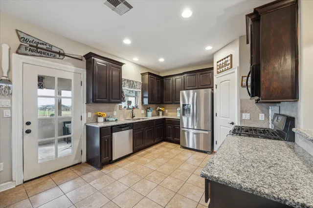 a kitchen with stainless steel appliances granite countertop a refrigerator and a sink
