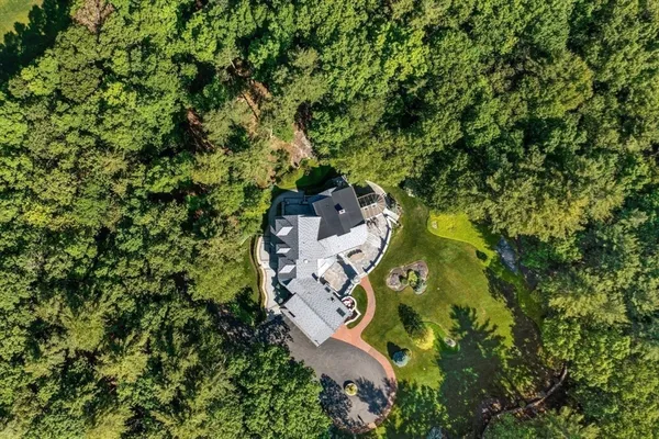 an aerial view of residential house with outdoor space and trees all around