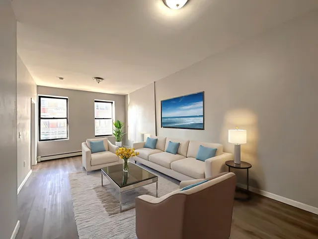 a living room with couches and a potted plant next to a window