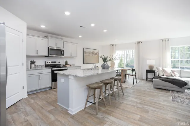 a kitchen with stainless steel appliances granite countertop a stove a sink a microwave a dining table and chairs