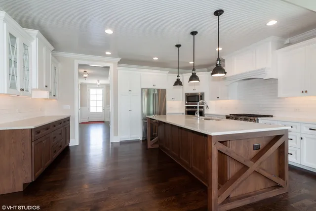 a kitchen with stainless steel appliances granite countertop a sink a stove a refrigerator and white cabinets with wooden floor