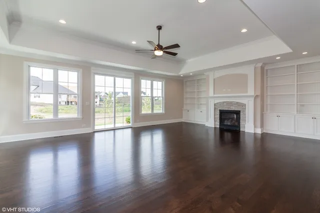 an empty room with wooden floor fireplace and windows