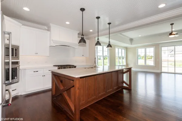 a kitchen with a stove a sink and wooden floor