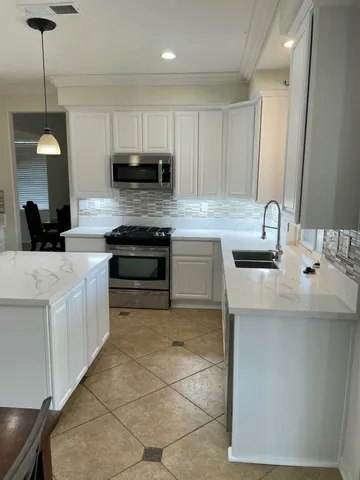 a kitchen with stainless steel appliances granite countertop a sink a stove top oven a counter space and cabinets