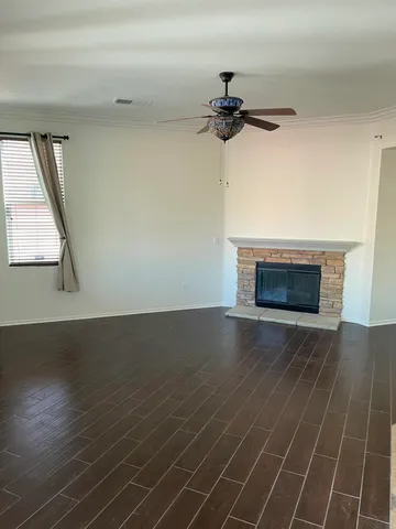 an empty room with wooden floor fireplace and windows