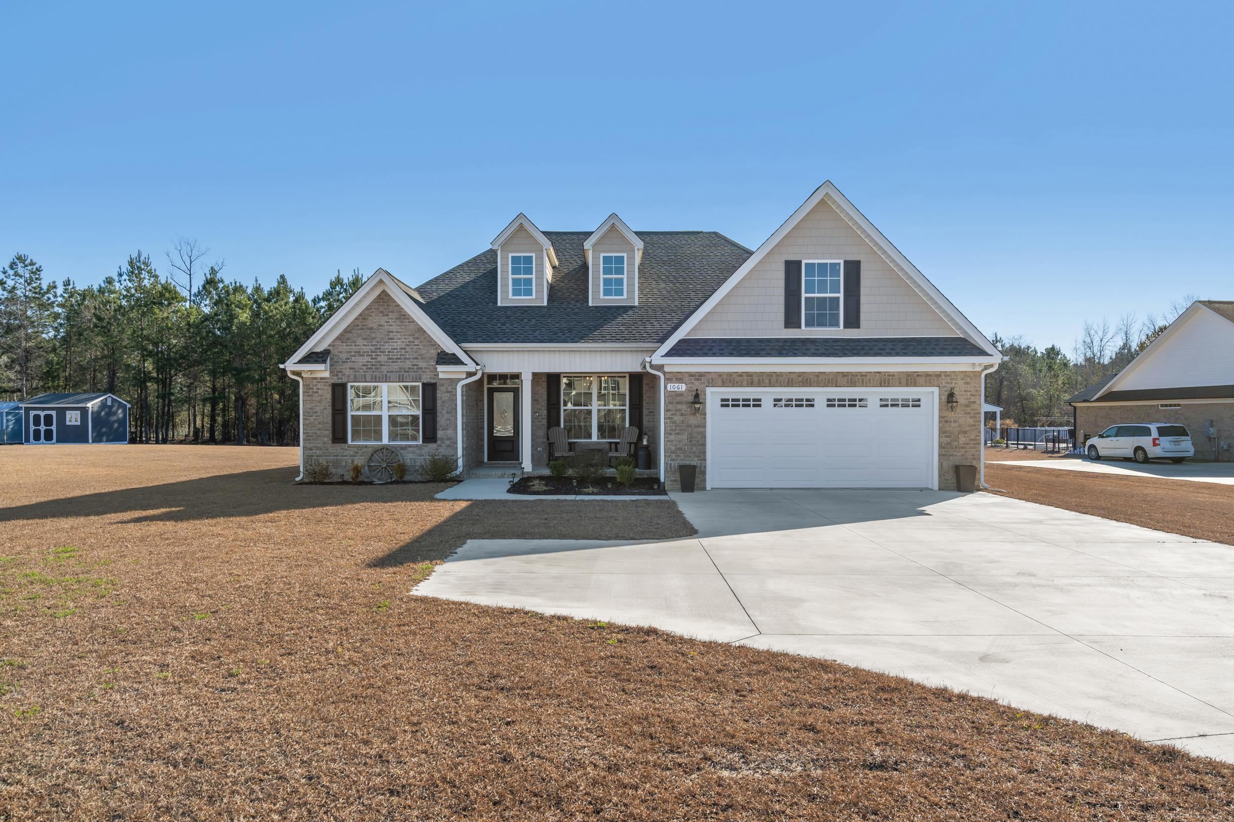 View of front of house with a porch, driveway, roof with shingles, and brick siding
