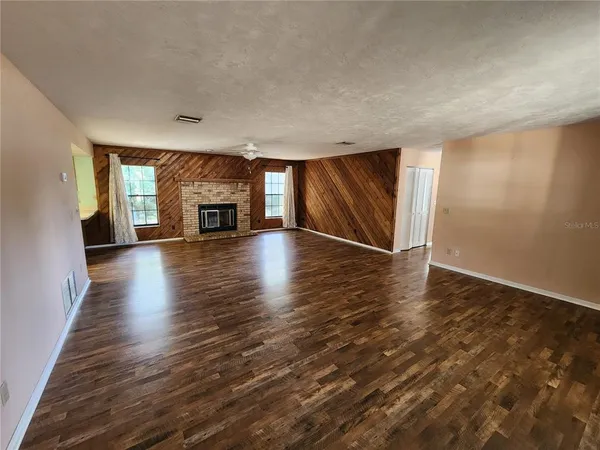 an empty room with wooden floor fireplace and mountain view