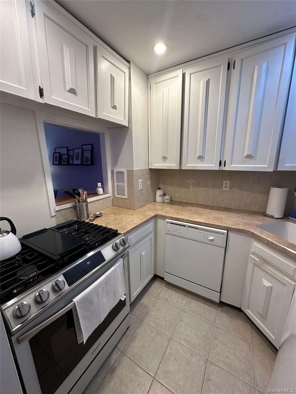 650 Shore Road, Unit 1C Long Beach, NY 11561 - Photo 8 of 21 a kitchen with granite countertop a stove sink and cabinets