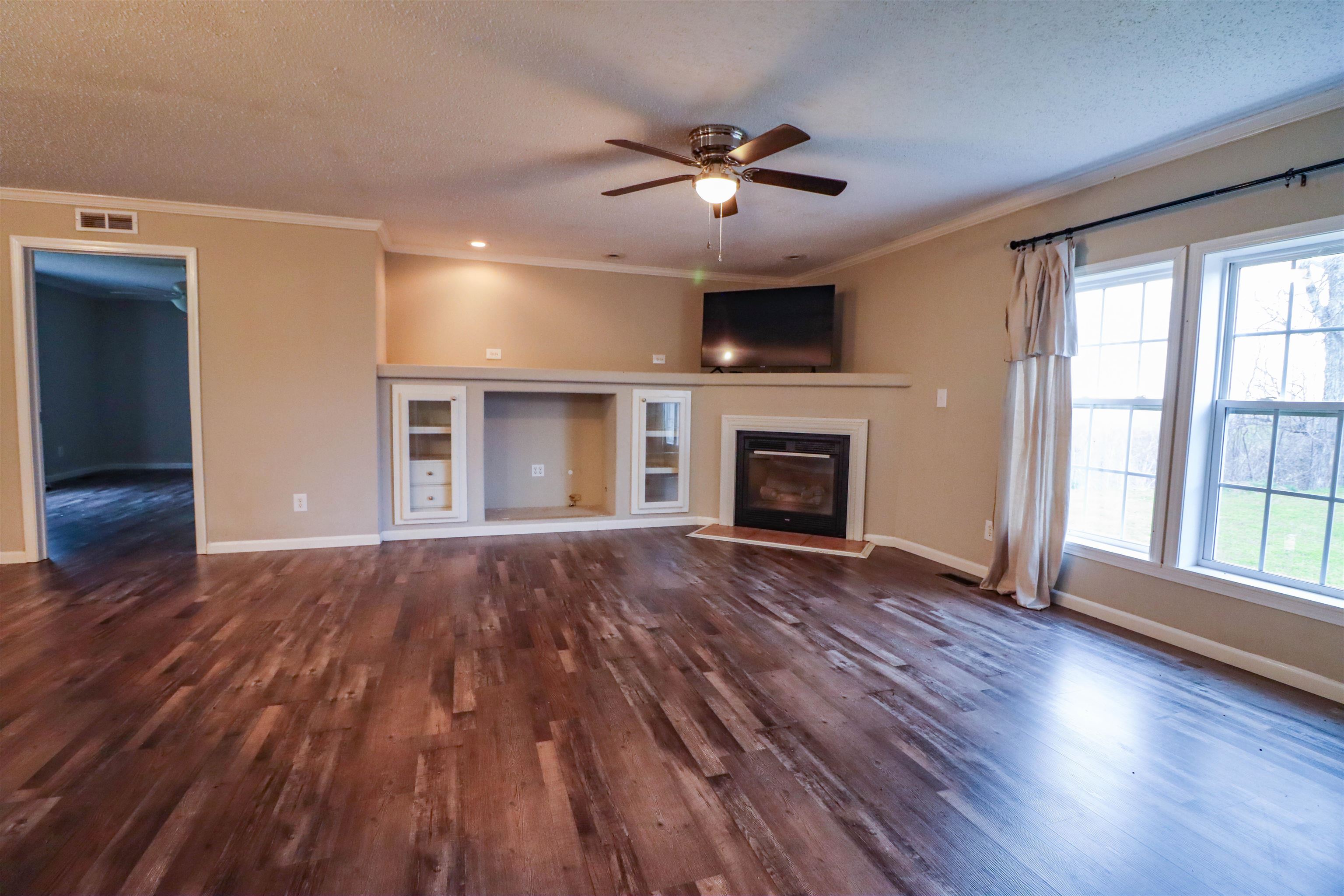 2914 Hobe Webb Road Ripley, TN 38063 - Photo 12 of 29 a view of an empty room with wooden floor fireplace and a window