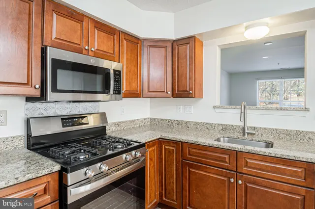 a kitchen with granite countertop a stove top oven microwave and cabinets