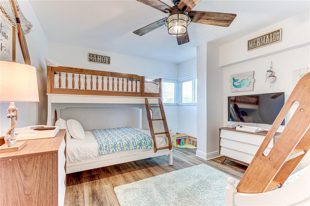 16332 Gulf Boulevard, Unit 1C Redington Beach, FL 33708 - Photo 25 of 90 a bedroom with a bed next to a window with a flat screen tv